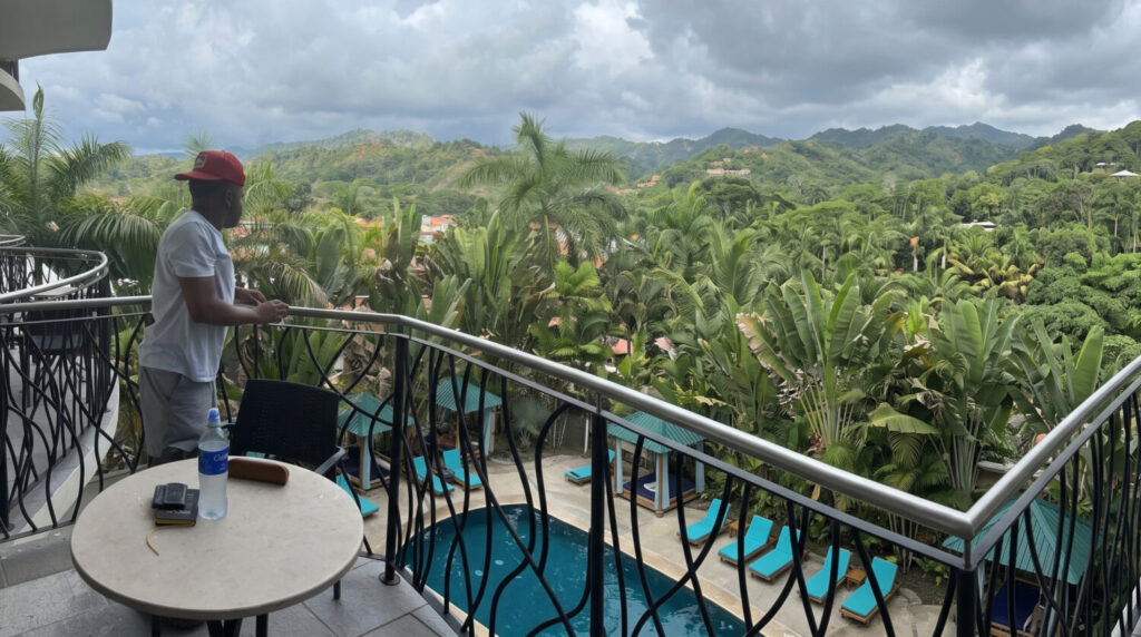 image of man standing at the balcony of his house looking at the environment